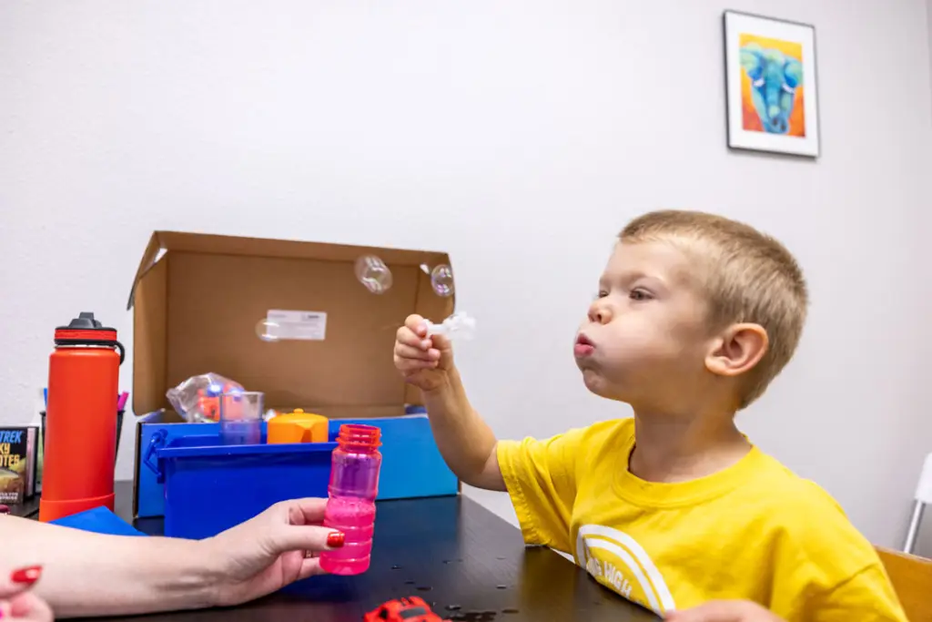 A young child blowing bubbles during a speech therapy exercise