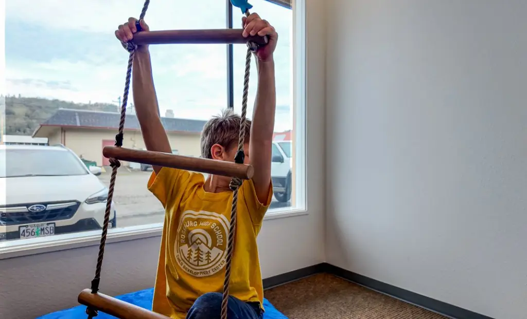 A boy climbing indoors during physical therapy in the children's clinic