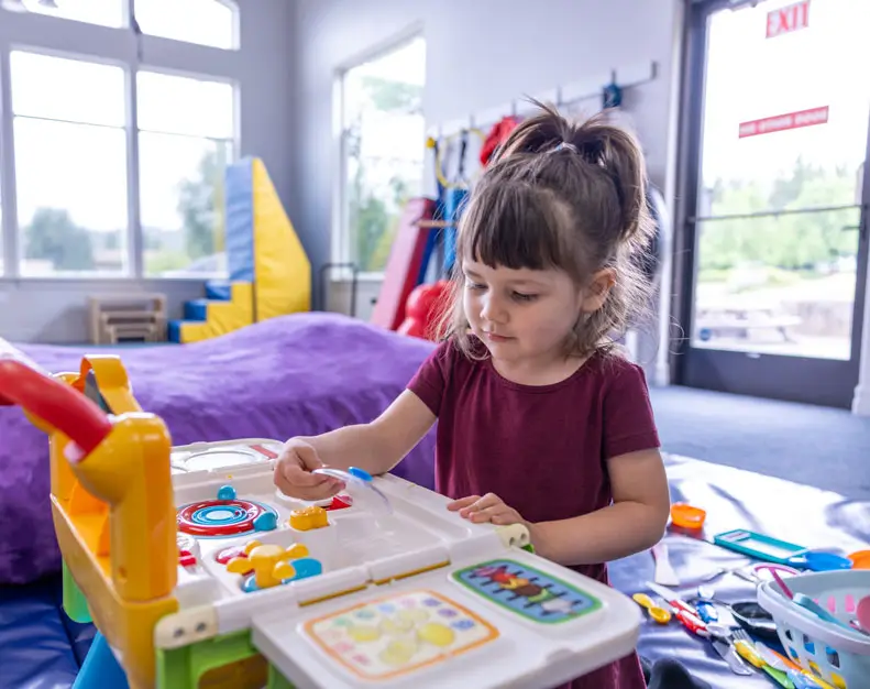 The main therapy playroom: swings, mats, a balance beam and a trampoline in a bright room