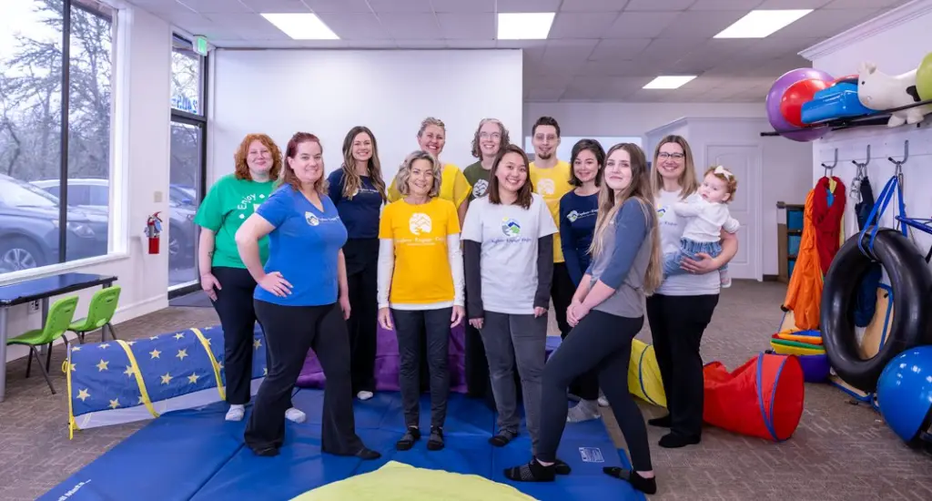 The whole Explore Engage Enjoy team standing together in the main playroom
